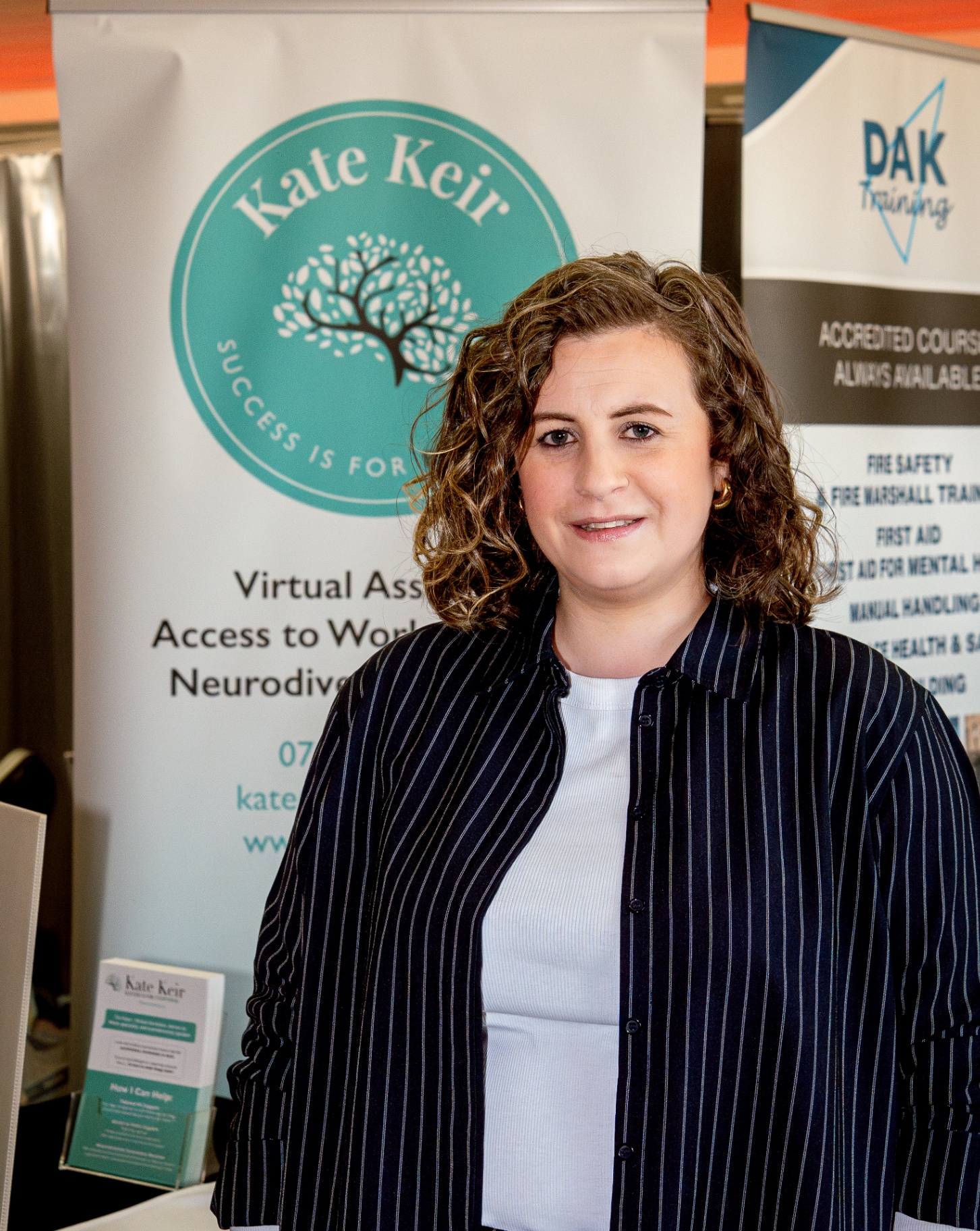 Kate Keir, founder, standing in front of her brand banner.