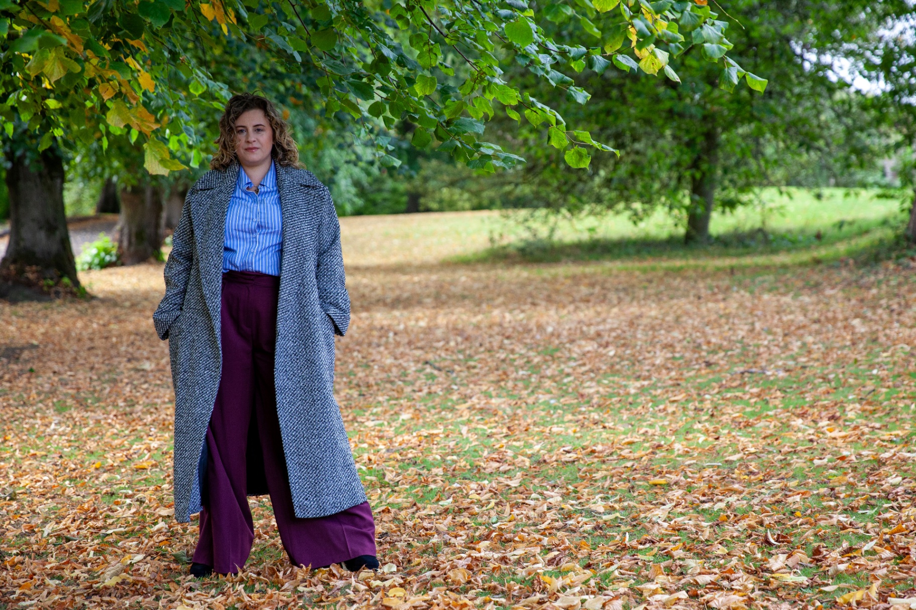 Kate Keir standing outdoors among autumn leaves, looking calm and confident.